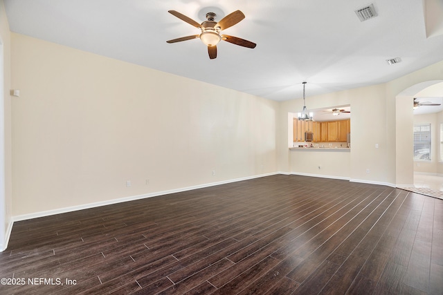 unfurnished living room with dark wood-type flooring, ceiling fan with notable chandelier, and visible vents