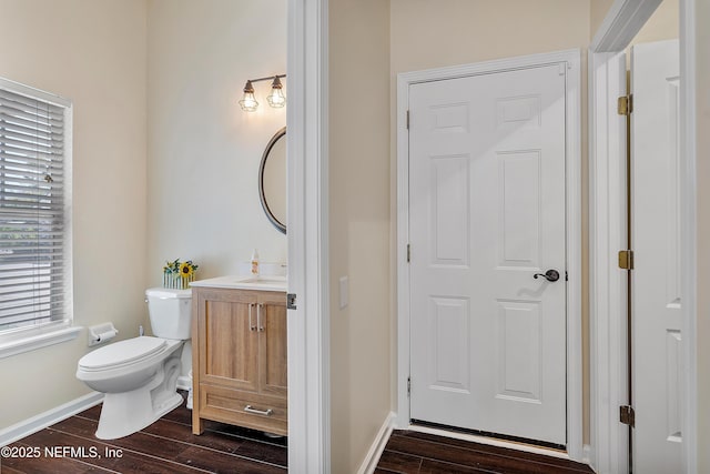 half bathroom featuring baseboards, vanity, toilet, and wood tiled floor