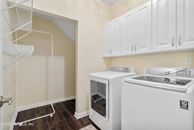 washroom featuring washer and dryer, cabinet space, baseboards, and wood tiled floor