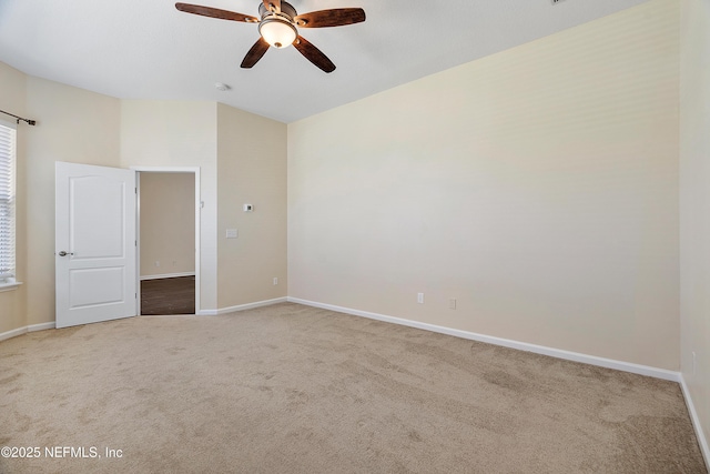 carpeted spare room with baseboards and a ceiling fan