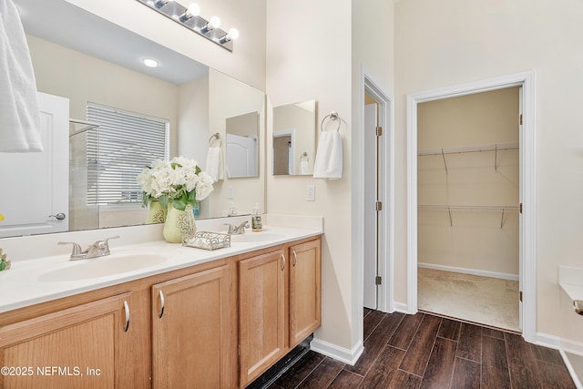 bathroom featuring a sink, a walk in closet, double vanity, and wood tiled floor