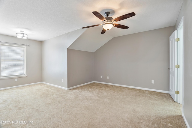 additional living space with baseboards, lofted ceiling, carpet flooring, a textured ceiling, and a ceiling fan