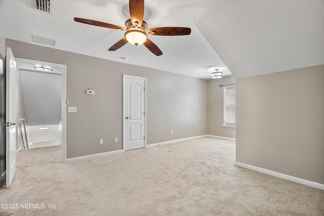 interior space with visible vents, a ceiling fan, a textured ceiling, baseboards, and light colored carpet