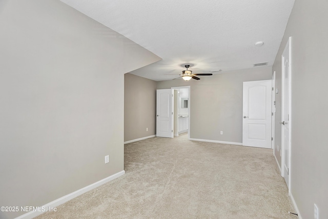 spare room featuring baseboards, visible vents, ceiling fan, a textured ceiling, and light carpet