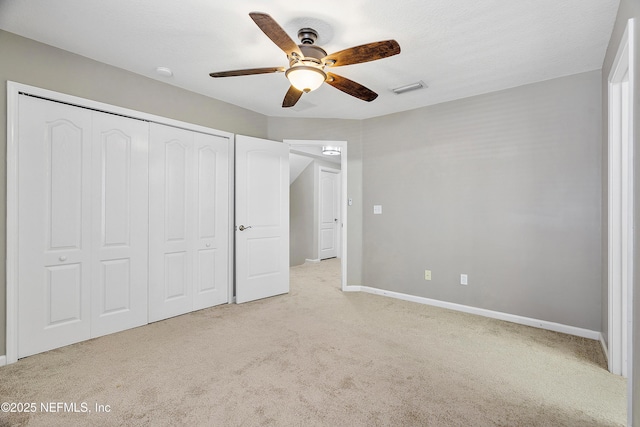 unfurnished bedroom with a ceiling fan, visible vents, baseboards, a closet, and light colored carpet