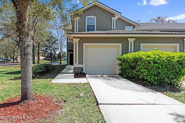 traditional home with an attached garage, driveway, and stucco siding