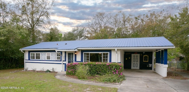 ranch-style home with stucco siding, a front lawn, metal roof, and driveway