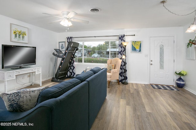 living room with visible vents, ceiling fan, baseboards, and wood finished floors