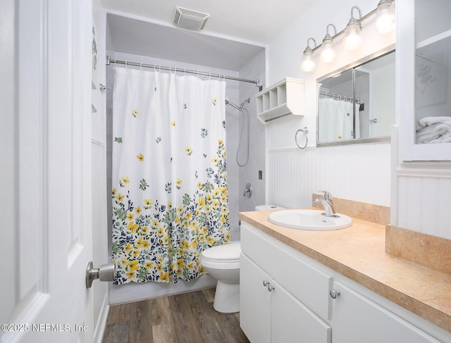 full bathroom with visible vents, shower / bath combo with shower curtain, toilet, wood finished floors, and vanity