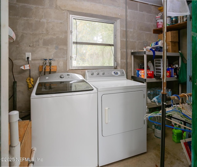 washroom featuring laundry area, washing machine and dryer, and concrete block wall