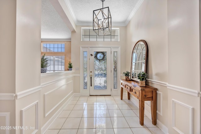 foyer with a textured ceiling, a decorative wall, a wainscoted wall, and ornamental molding