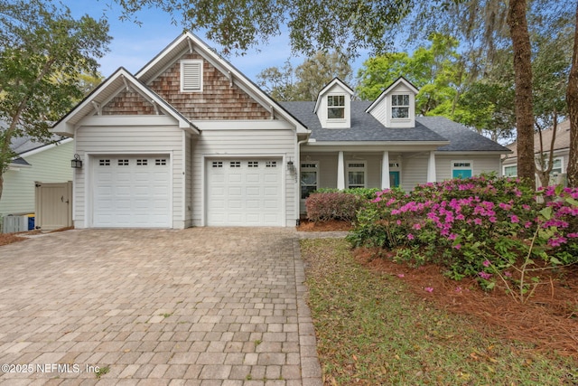 view of front facade with a garage, decorative driveway, and a shingled roof