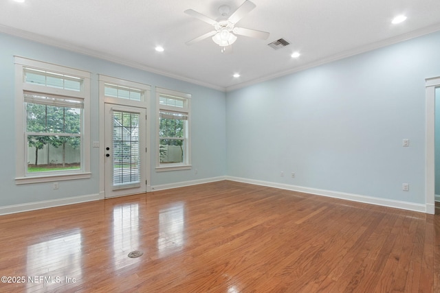 spare room featuring plenty of natural light, wood finished floors, visible vents, and ornamental molding