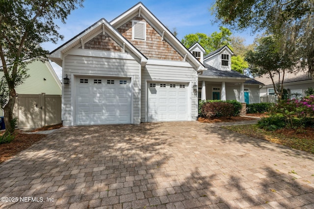 view of front of home featuring decorative driveway, a garage, and fence