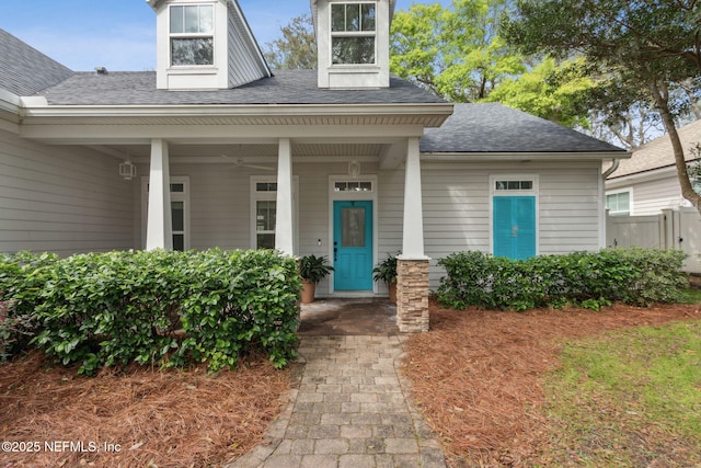 property entrance with ceiling fan and a shingled roof