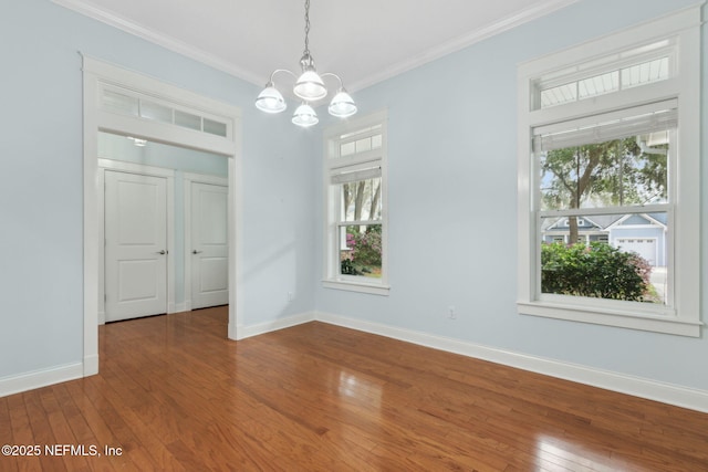 unfurnished dining area featuring baseboards, a notable chandelier, ornamental molding, and hardwood / wood-style flooring