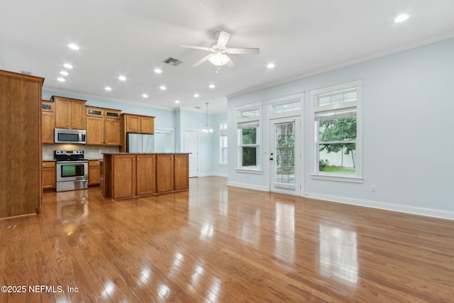 kitchen with visible vents, open floor plan, appliances with stainless steel finishes, brown cabinetry, and light wood finished floors