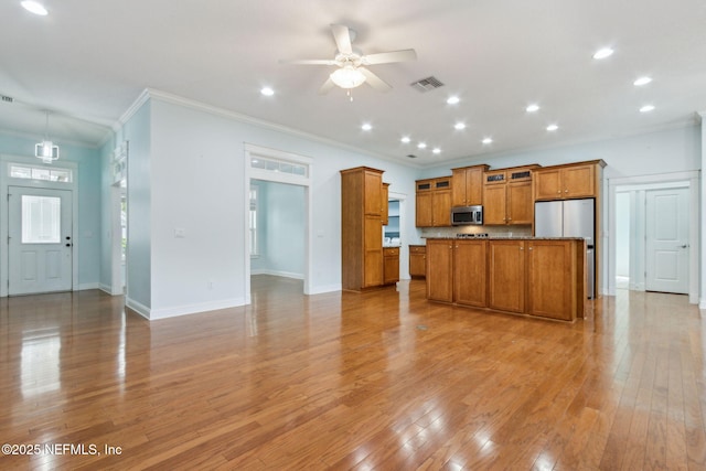 kitchen with stainless steel appliances, brown cabinets, open floor plan, and light wood-style flooring