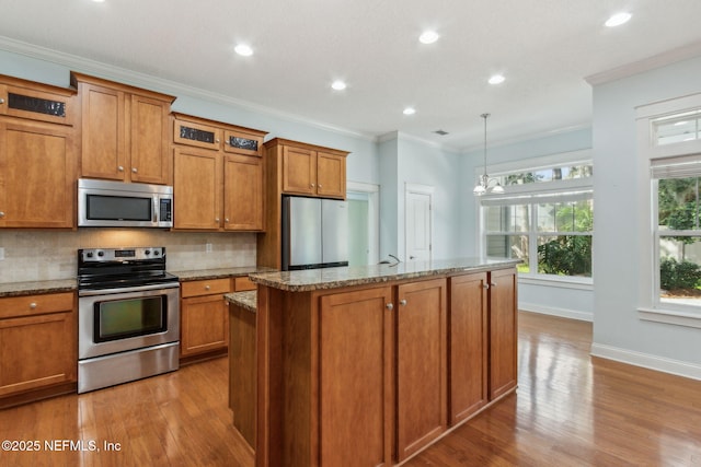 kitchen featuring ornamental molding, brown cabinetry, backsplash, and stainless steel appliances