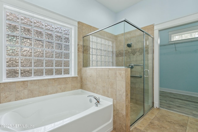 bathroom featuring a bath, a shower stall, and a walk in closet