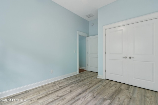 unfurnished bedroom with visible vents, baseboards, light wood-type flooring, and a closet