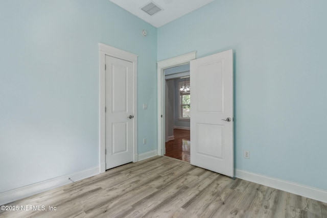 unfurnished bedroom with visible vents, baseboards, an inviting chandelier, and light wood finished floors