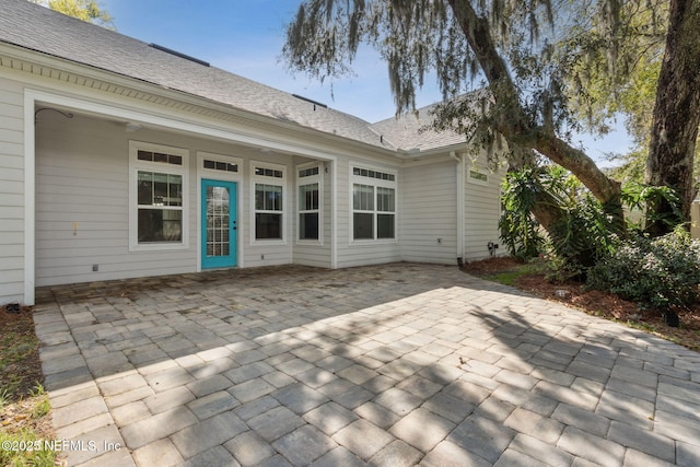 rear view of house with a shingled roof and a patio