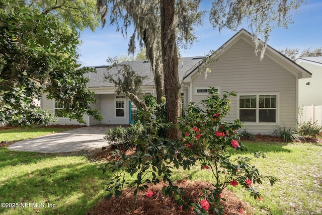 back of house with a yard, driveway, and a shingled roof