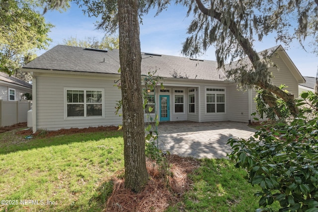 back of property featuring a lawn, roof with shingles, a patio, and fence