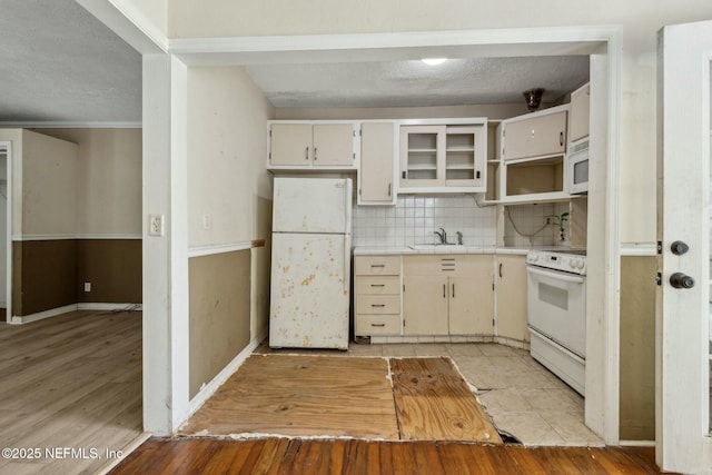 kitchen featuring tasteful backsplash, tile countertops, light wood-style flooring, white appliances, and a textured ceiling