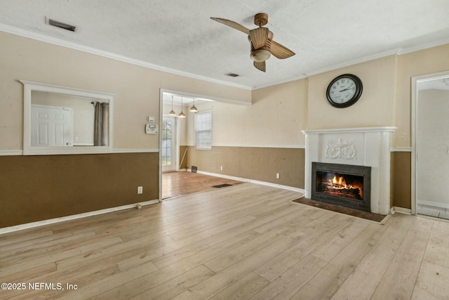 unfurnished living room with visible vents, wood-type flooring, ceiling fan, and crown molding