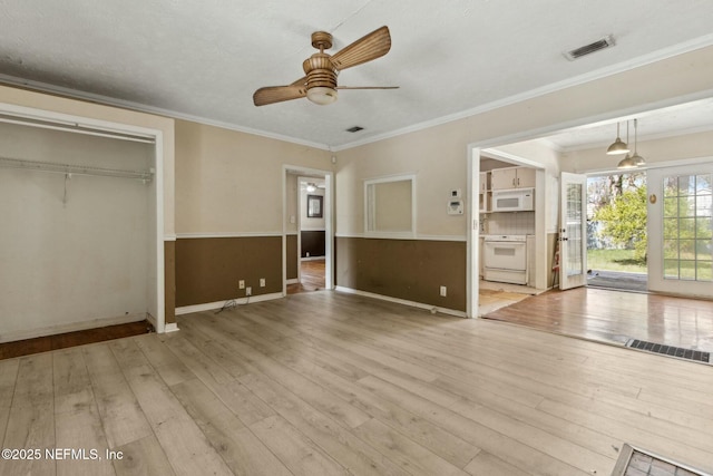 interior space with visible vents, a ceiling fan, hardwood / wood-style floors, and crown molding