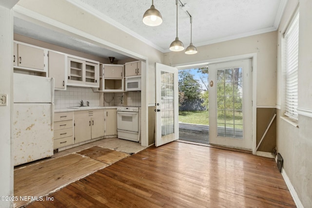 kitchen with light countertops, light wood-type flooring, ornamental molding, decorative backsplash, and white appliances