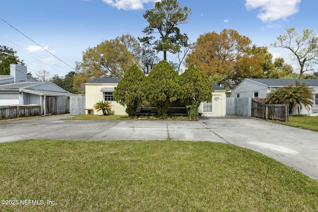 view of front of property with stucco siding, driveway, a front lawn, and fence