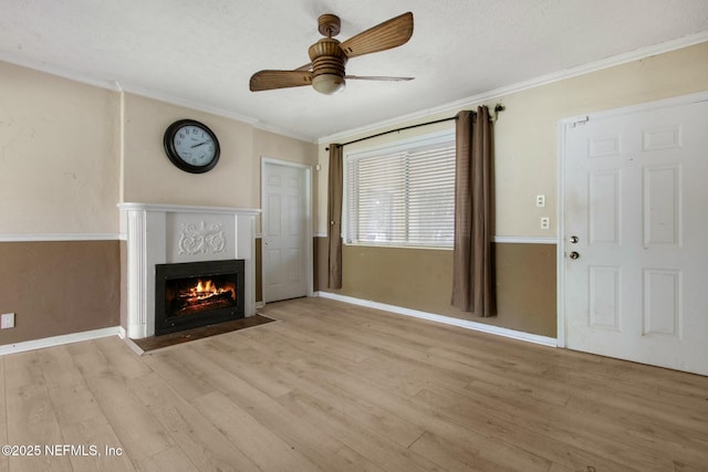 unfurnished living room featuring a fireplace with flush hearth, crown molding, ceiling fan, and wood finished floors