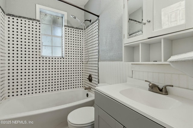 bathroom with a wainscoted wall, vanity, toilet, and shower / bathing tub combination