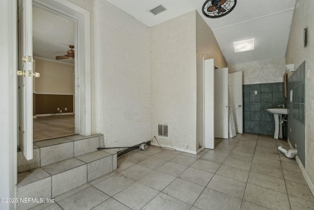 interior space with tile patterned flooring, tile walls, visible vents, and a sink