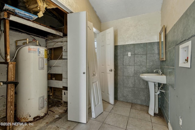 bathroom featuring water heater, tile patterned floors, tile walls, and a sink