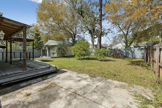 view of yard with a wooden deck, an outdoor structure, a fenced backyard, and a patio area