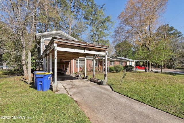 view of front of home with a front yard, driveway, a carport, a trampoline, and brick siding