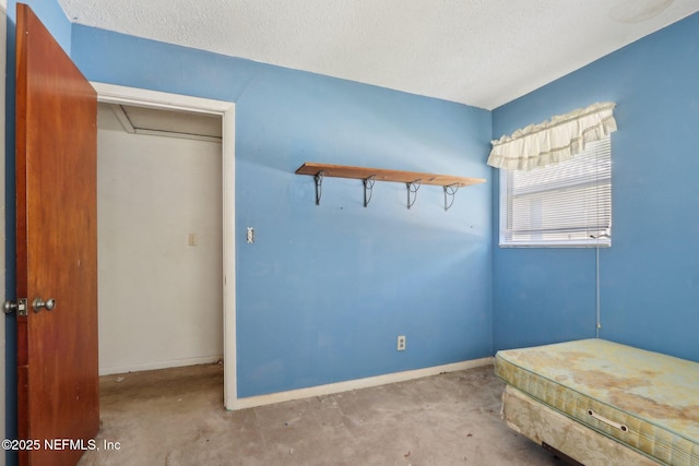 unfurnished bedroom featuring attic access, baseboards, and a textured ceiling