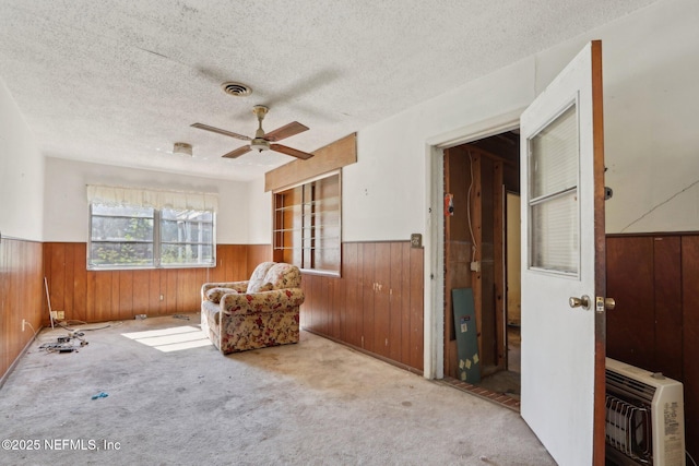 living area with heating unit, a wainscoted wall, and carpet flooring