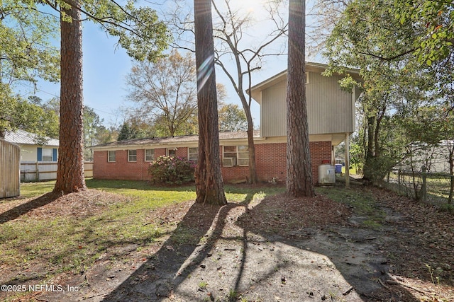 rear view of house featuring brick siding and fence