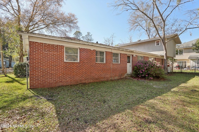 view of home's exterior featuring brick siding, a yard, and fence