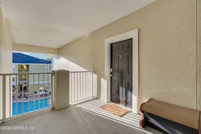 view of exterior entry with a balcony and stucco siding