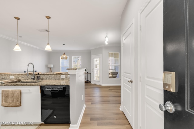 kitchen with ornamental molding, a sink, decorative light fixtures, black dishwasher, and light wood finished floors