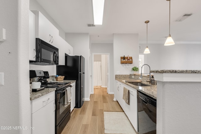 kitchen with white cabinetry, black appliances, visible vents, and a sink