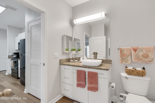 bathroom with visible vents, baseboards, toilet, wood finished floors, and vanity