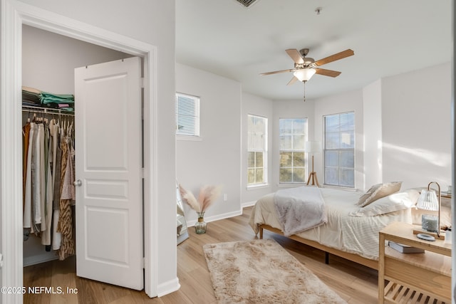 bedroom with baseboards, multiple windows, and wood finished floors