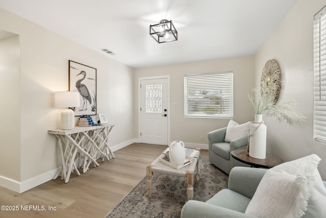 living room featuring visible vents, baseboards, and light wood-style floors